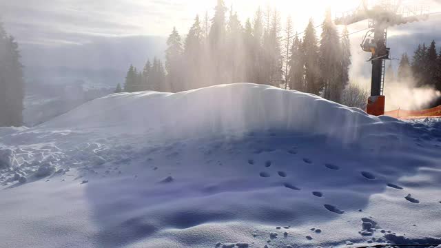 滑雪胜地的雪炮。造雪机在阳光和滑雪缆车的背景下制造人造雪。人工造雪的美妙景象。滑雪胜地的工作视频素材