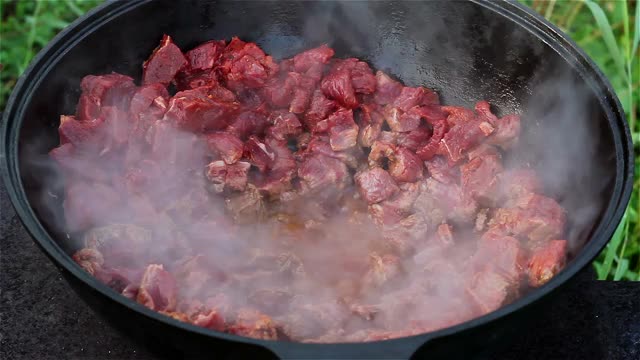 东方菜肴的烹饪过程。红肉在一个大锅里用油煮沸和炖。大型传统亚洲锅在明火上，称为喀山视频下载