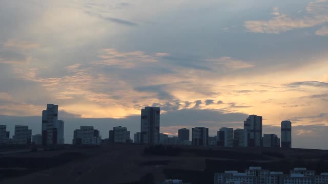 鸟儿在多云的日落与矮和高的建筑城市景观飞行视频下载