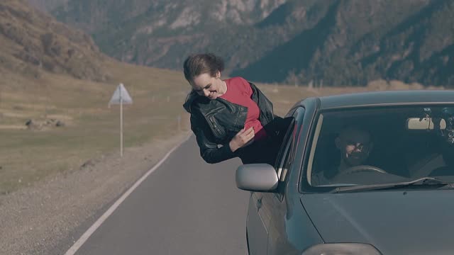 汽车沿着漫长的道路行驶，女士从车窗探出身子视频素材