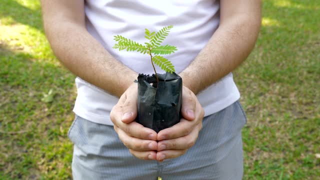 带着土壤、生态、生命理念的花盆袋里抱着嫩芽的男人视频素材