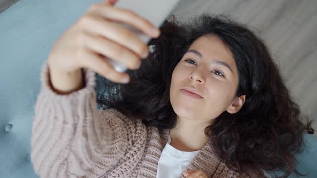 美丽的混血女子在家里用智能手机自拍视频素材