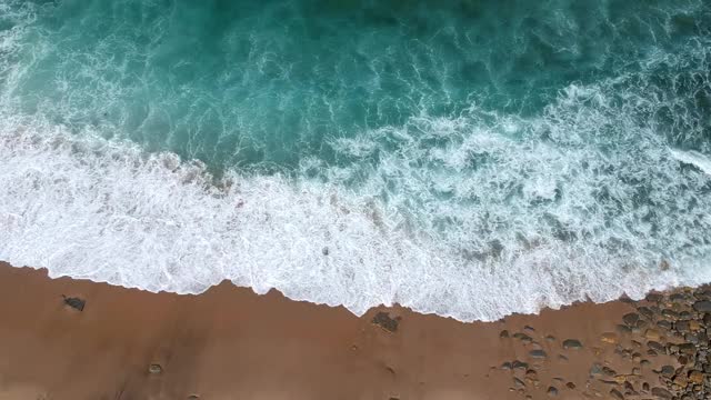 无人机的美丽的绿松石海浪打破了沙滩海岸线。航拍的金色海滩遇见深蓝色的海水和泡沫的波浪。视频素材