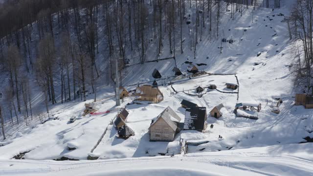 冬季村滑雪场上的雪林和山地景观。在阳光明媚的日子里，在雪坡上运送滑雪者和滑雪板的滑雪缆车。4 k鸟瞰图视频素材