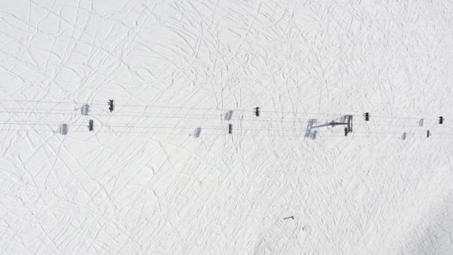 冬季滑雪场缆车上的高空鸟瞰图。滑雪升降机升降机，用于运输冬季滑雪者和滑雪板滑雪者在雪山度假村4k视频素材