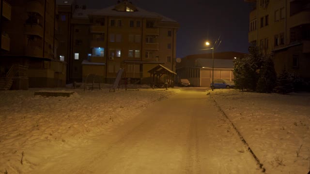 晚上，积雪覆盖的住宅楼前空荡荡的操场视频素材