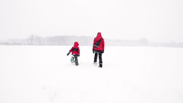 母亲和儿子在冬天雪鞋户外在暴风雪视频素材