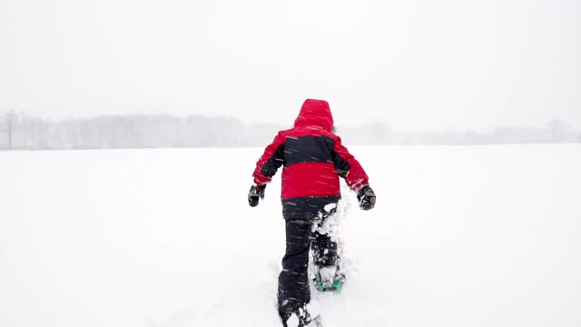 小男孩在暴风雪期间在户外穿雪鞋视频素材