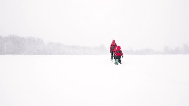 母亲和儿子在冬天雪鞋户外在暴风雪视频素材