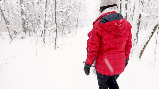 母亲和儿子在冬天雪鞋户外在暴风雪视频素材