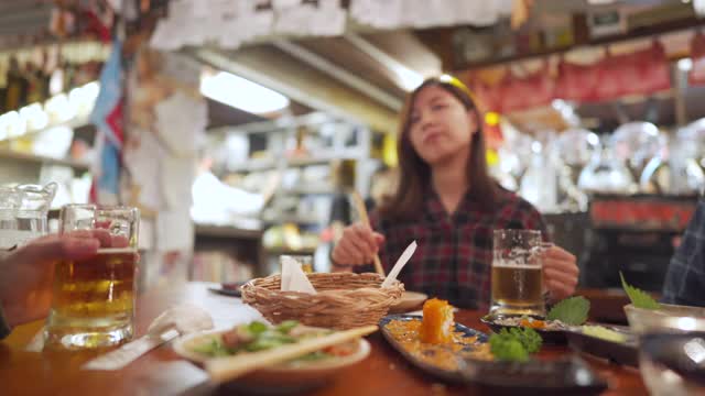 亚洲妇女欢呼与啤酒与朋友在日本餐厅视频素材