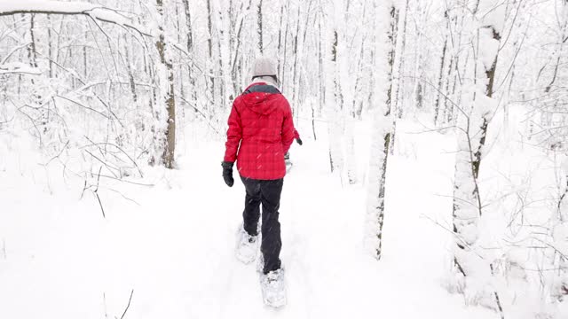 母亲和儿子在冬天雪鞋户外在暴风雪视频素材