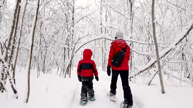 母亲和儿子在冬天雪鞋户外在暴风雪视频素材