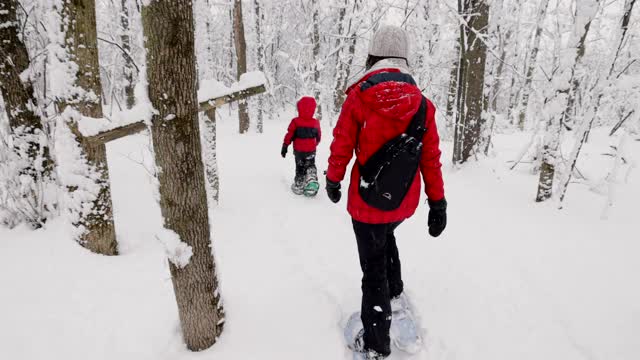 母亲和儿子在冬天雪鞋户外在暴风雪视频素材