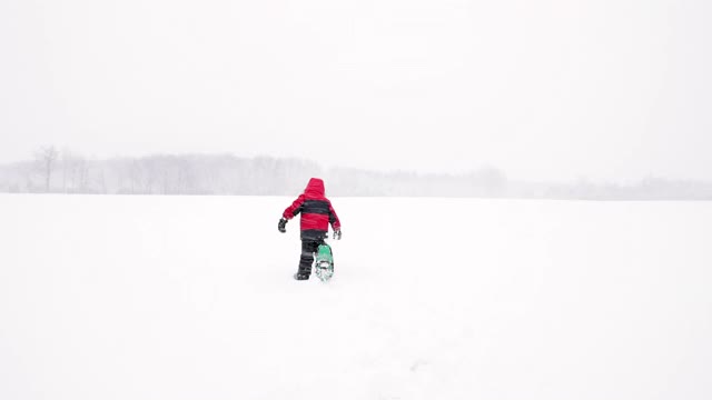 小男孩在暴风雪期间在户外穿雪鞋视频素材