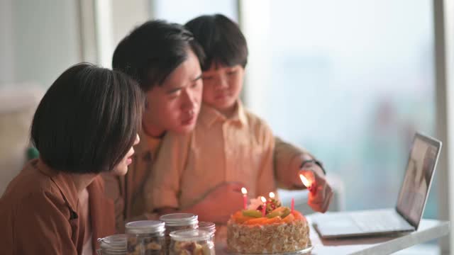 视频电话给爷爷奶奶，亚洲华人家庭在客厅为儿子唱歌和鼓掌庆祝生日视频素材