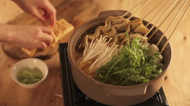 冬季食物-将鱼饼汤的食材放入煮熟的肉汤中视频素材