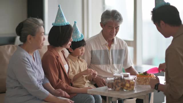 亚洲华人多代家庭庆祝生日，用菜刀切生日蛋糕视频素材