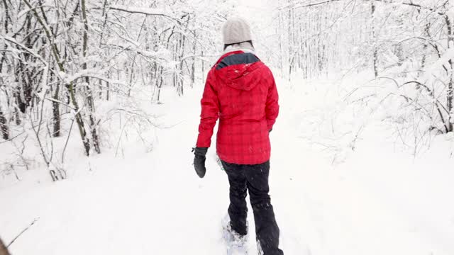 母亲和儿子在冬天雪鞋户外在暴风雪视频素材