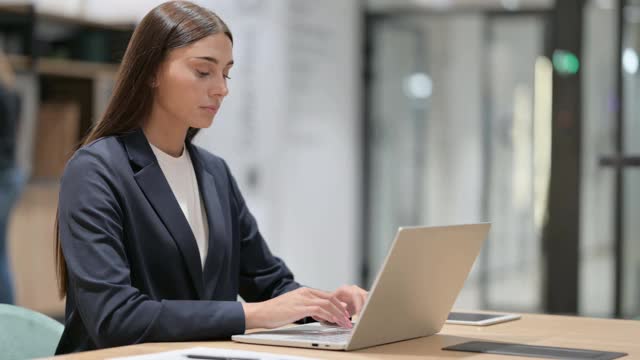 美丽的女商人在办公室用笔记本电脑庆祝成功视频素材