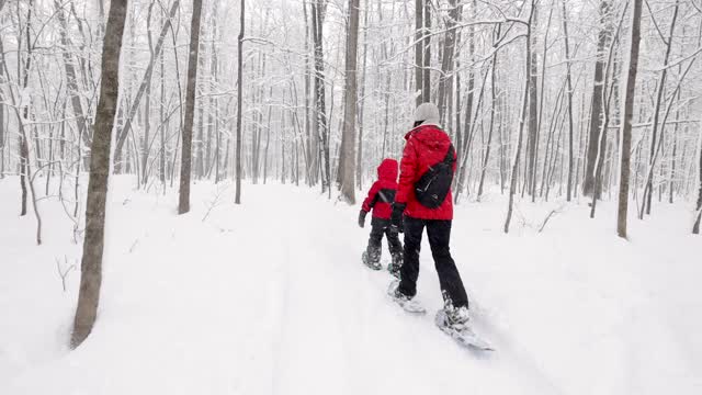 母亲和儿子在冬天雪鞋户外在暴风雪视频素材