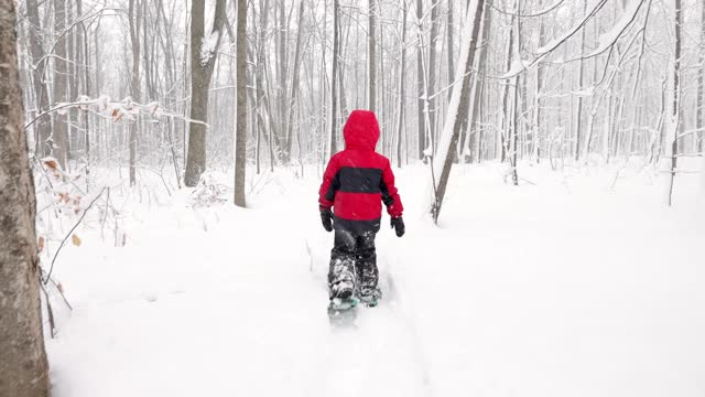 在暴风雪期间，小男孩和他的家人在户外穿雪鞋视频素材