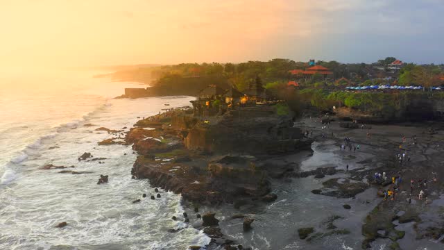 Pura Tanah Lot寺庙在海滩上日落在巴厘岛的海边，印度尼西亚。一座寺庙的剪影。4 k鸟瞰图视频素材