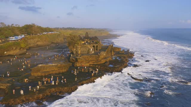 游客们走进印度教寺庙Pura Tanah lot，这是印度尼西亚巴厘岛最受欢迎的日落景观之一。4 k鸟瞰图视频素材