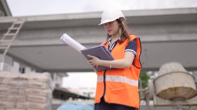 亚洲华裔女建筑师在工地上用数字平板展示建筑进展。视频素材