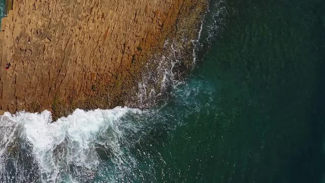 怀旧的航空视频，在缓慢的动作的海洋，波浪平稳地滚在岩石海岸的太平洋大西洋。视频素材