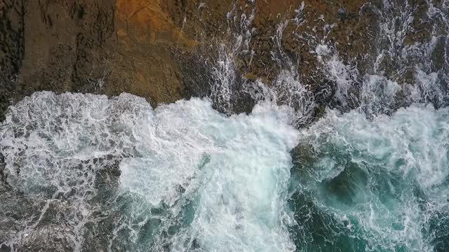 怀旧的航空视频，在缓慢的动作的海洋，波浪平稳地滚在岩石海岸的太平洋大西洋。视频素材