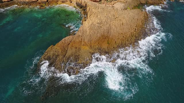 怀旧的航空视频，在缓慢的动作的海洋，波浪平稳地滚在岩石海岸的太平洋大西洋视频素材