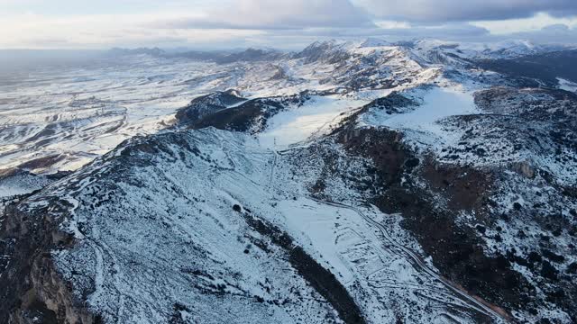 多云天空下雪山景观鸟瞰图。冬天的无人机视频。高质量4k镜头视频素材