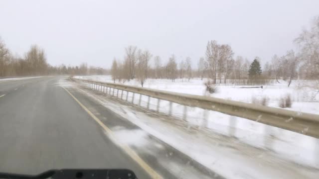 暴风雪在高速公路上从汽车的窗口，一条危险的冰路和雨视频素材