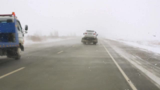 这是冰天雪地的危险路线，两辆拖车在运送汽车视频素材