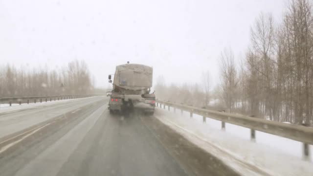 暴风雪在高速公路上从车窗向外袭来，路面结冰危险。拾雪机清理道路视频素材