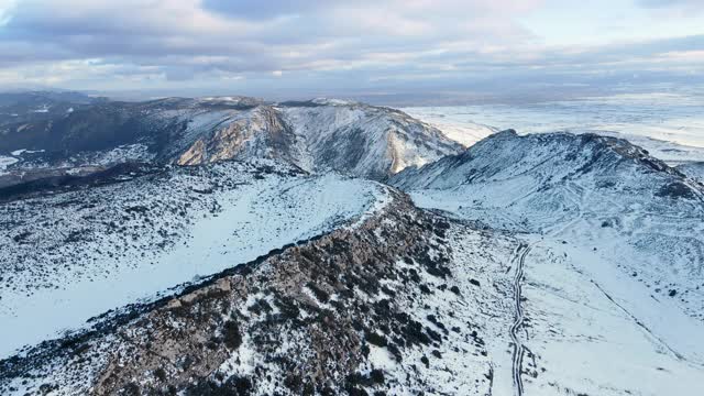 多云天空下雪山景观鸟瞰图。冬天的无人机视频。高质量4k镜头视频素材