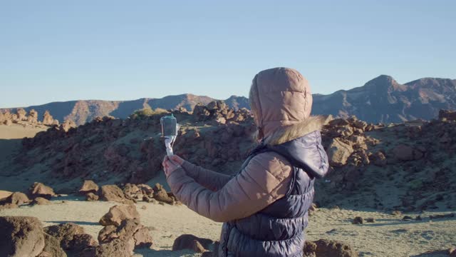 在寒冷多风的天气里，漂亮女孩的视频博主与火星景观自拍视频素材