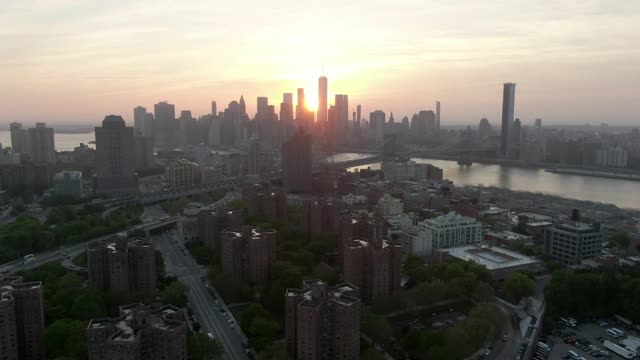 空中拍摄的桥梁在东河在城市的建筑物，无人机飞向曼哈顿的天空在日落-纽约市，纽约视频素材