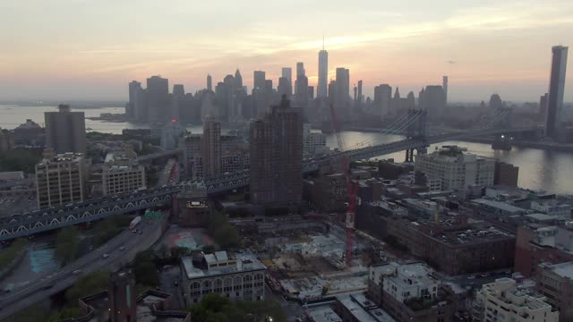 航拍的街道和建筑物在城市的东河，无人机从曼哈顿向后飞行的天空在日落-纽约市，纽约视频素材