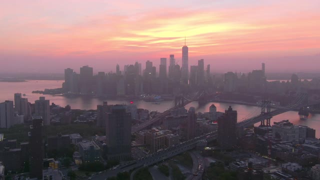 空中拍摄的城市东河上的桥梁对天空，无人机飞向曼哈顿的建筑物在日落-纽约市，纽约视频素材