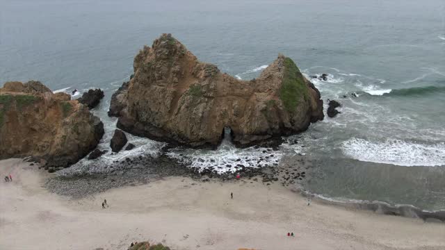 空中封锁拍摄人们在海滩上著名的锁眼拱门，无人机在海浪上飞溅-大苏尔，加利福尼亚视频素材