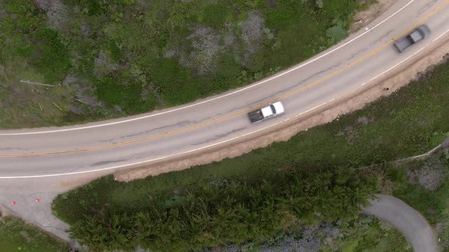 空中拍摄在绿色植物中道路上的车辆，无人机飞过汽车在公路旅行-大苏尔，加利福尼亚视频素材