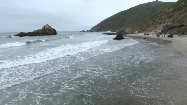 航拍的海浪拍打海岸对天空，无人机上升朝着山在海滩-大苏尔，加利福尼亚视频素材