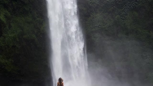 慢动作倾斜下惊人的塞坎普尔瀑布和女人享受的风景-巴厘岛，印度尼西亚视频素材