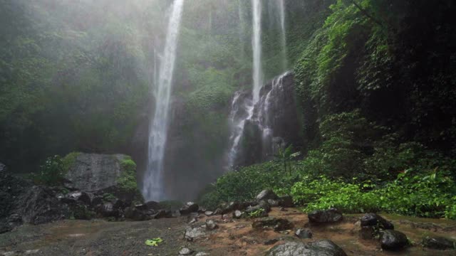 慢镜头倾斜的冲泻瀑布在迷雾中的雨林与闪光的岩石和郁郁葱葱的热带植物-巴厘岛，印度尼西亚视频素材