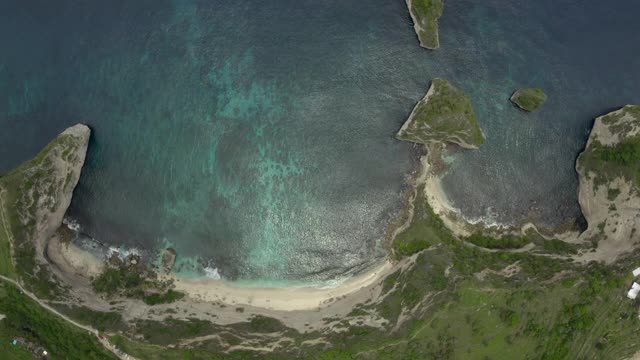 空中垂直向下的热带海滩海湾坐落在陡峭的悬崖边上，绿松石的水，珊瑚，岩石，和拍打的海浪-努沙佩尼达&龙目岛，巴厘岛视频素材