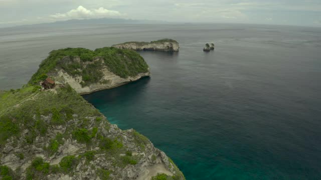 空中淘金宁静的海滩和岩层，热带绿松石水域，珊瑚礁，和朦胧的海洋天空延伸到地平线-努沙佩尼达和龙目岛，巴厘岛视频素材