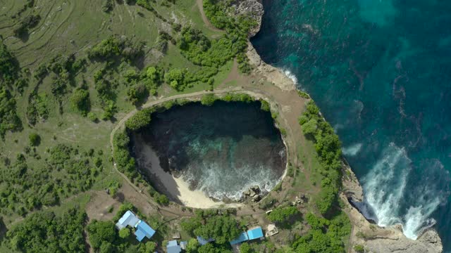 空中慢速旋转到一个封闭的热带海滨海湾，海浪拍打，绿松石的水域，茂盛的热带植物下的阳光天空-努沙佩尼达和龙目岛，巴厘岛视频素材