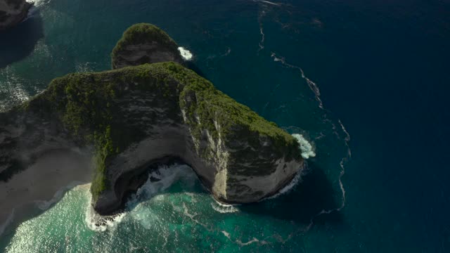 空中淘金高在陡峭的海滩悬崖突出到蓝绿色的海水漩涡波，热带海湾，和沙滩，阳光普照的海滩-努沙佩尼达和龙目岛，巴厘岛视频素材